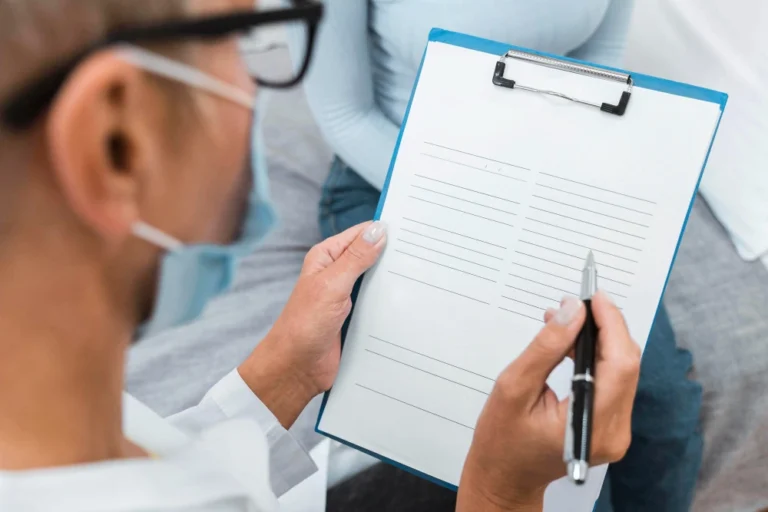 Doctor writing a hair transplant pre-op checklist to hand to a patient during consultation