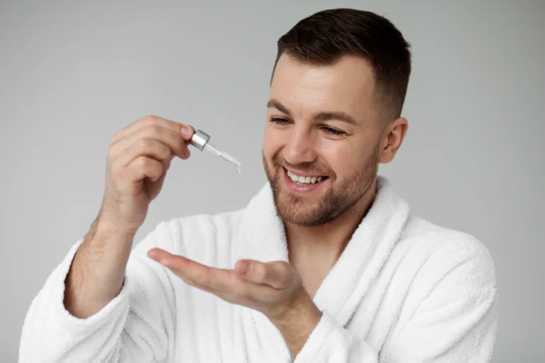 Man holding a minoxidil solution dropper, applying 5% to thinning scalp