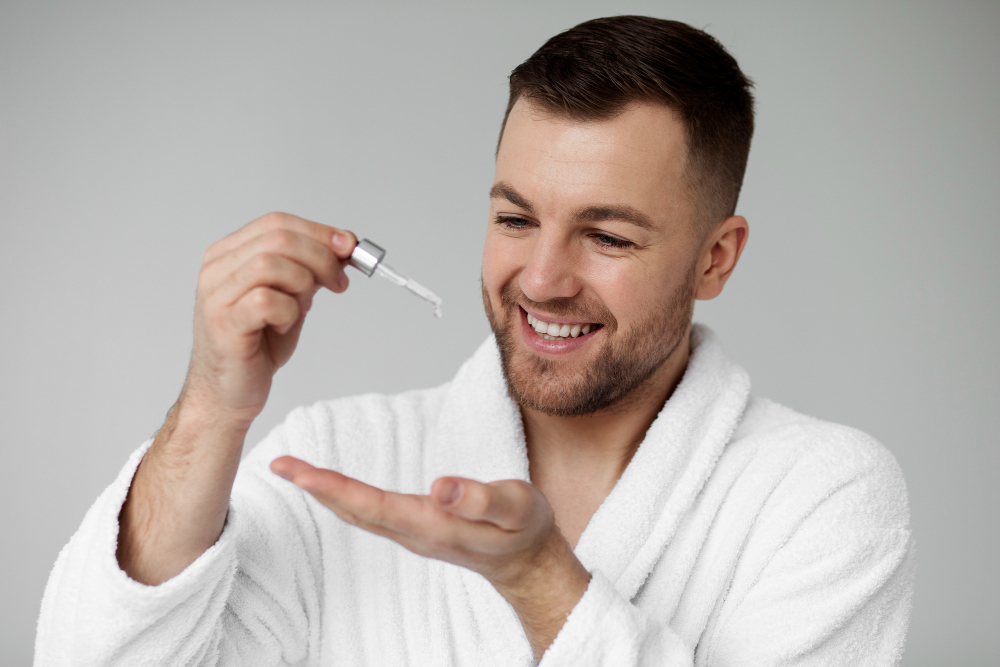 Man holding a minoxidil solution dropper, applying 5% to thinning scalp