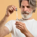 Man holding a topical finasteride bottle, preparing to apply to thinning scalp