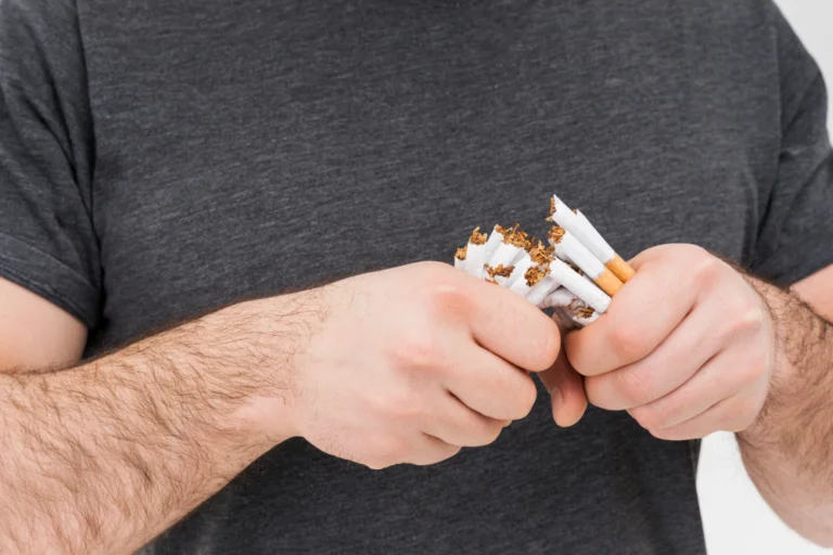 Man breaking a cigarette pack in half with both hands to improve hair and overall health