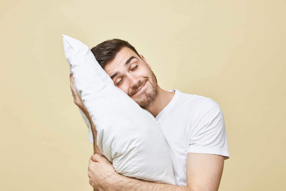 Well-rested and it shows: a man with healthy-looking hair sleeps peacefully, hugging a pillow—consistent 7–9 hours may help reduce stress-related shedding.