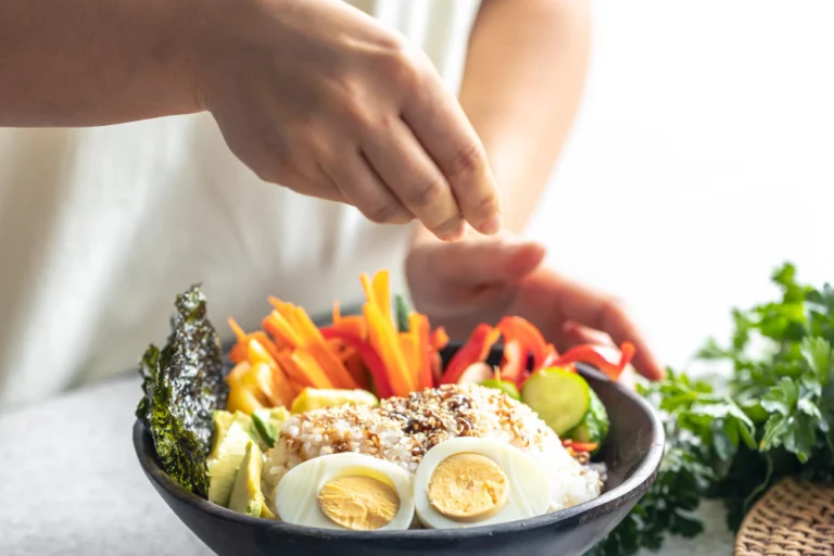 Woman finishing a healthy meal prep with protein, leafy greens, legumes and healthy fats to support hair growth